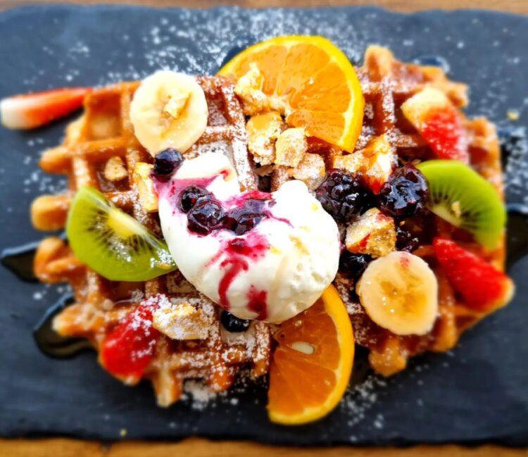 Belgian waffles with berry compote, ice cream, nut crumble, fresh fruit & honeycomb at Tea Gardens Boastshed.